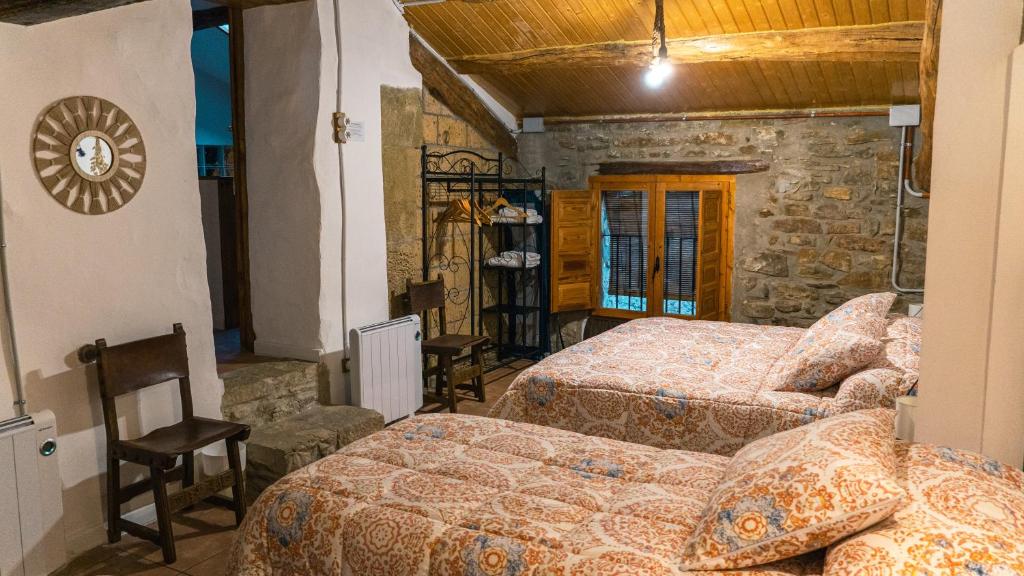 a bedroom with two beds and a stone wall at Cal Belló Casa rural in Lleida