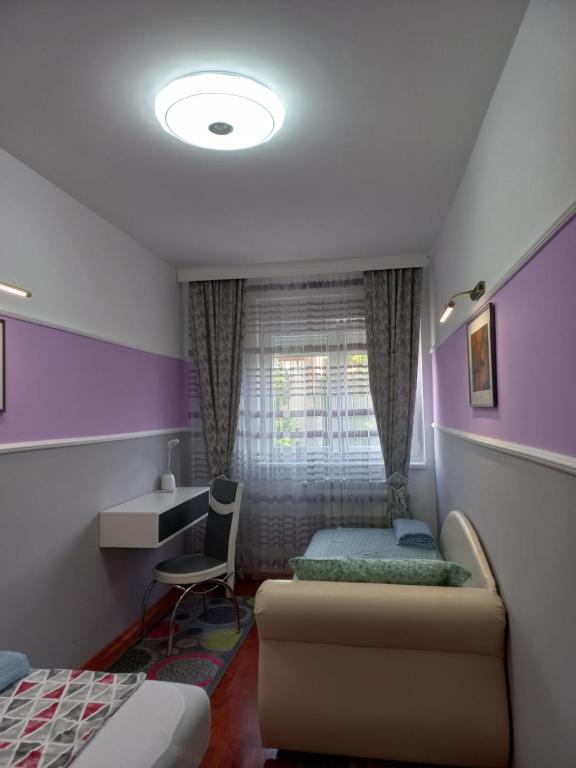 a bedroom with a bed and a desk and a window at Twins Apartments in Čačak