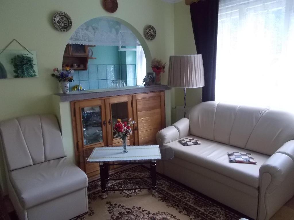 a living room with two chairs and a couch and a table at Pensiunea Ibolya in Băile Tuşnad