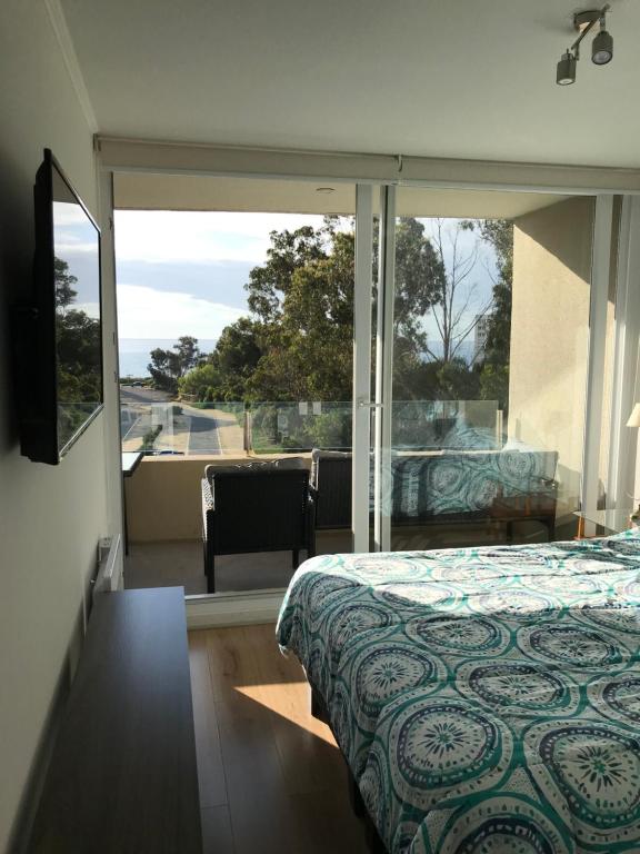 Schlafzimmer mit einem Bett und einem großen Glasfenster in der Unterkunft Hermoso Departamento a 5 min. caminando a la playa in Papudo