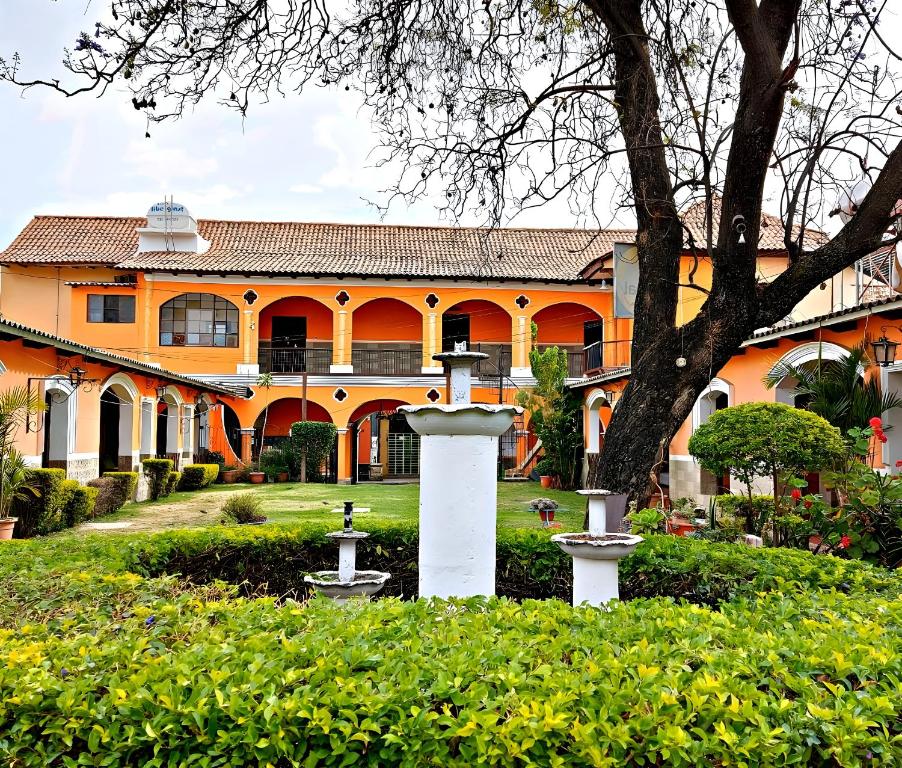 an orange building with a fountain in front of a yard at Ñaupa House Hostel in Cochabamba