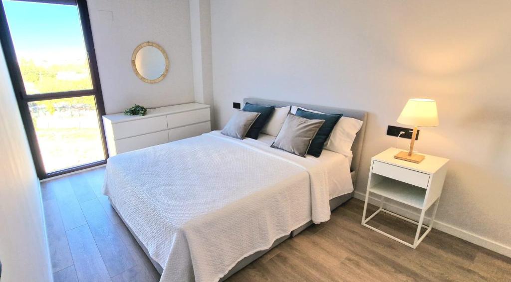 ein weißes Schlafzimmer mit einem Bett und einem Tisch mit einer Lampe in der Unterkunft Tina de Vila, en la capital del vino in Vilafranca del Penedès