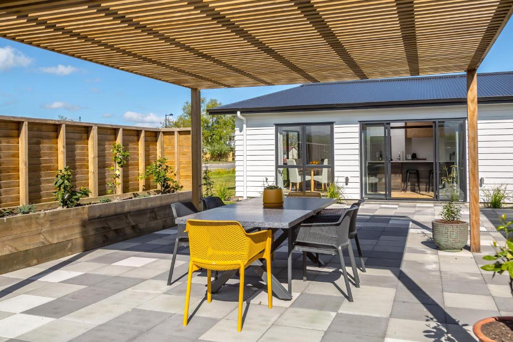 een patio met een tafel en stoelen onder een houten pergola bij Citron 9 in Greytown