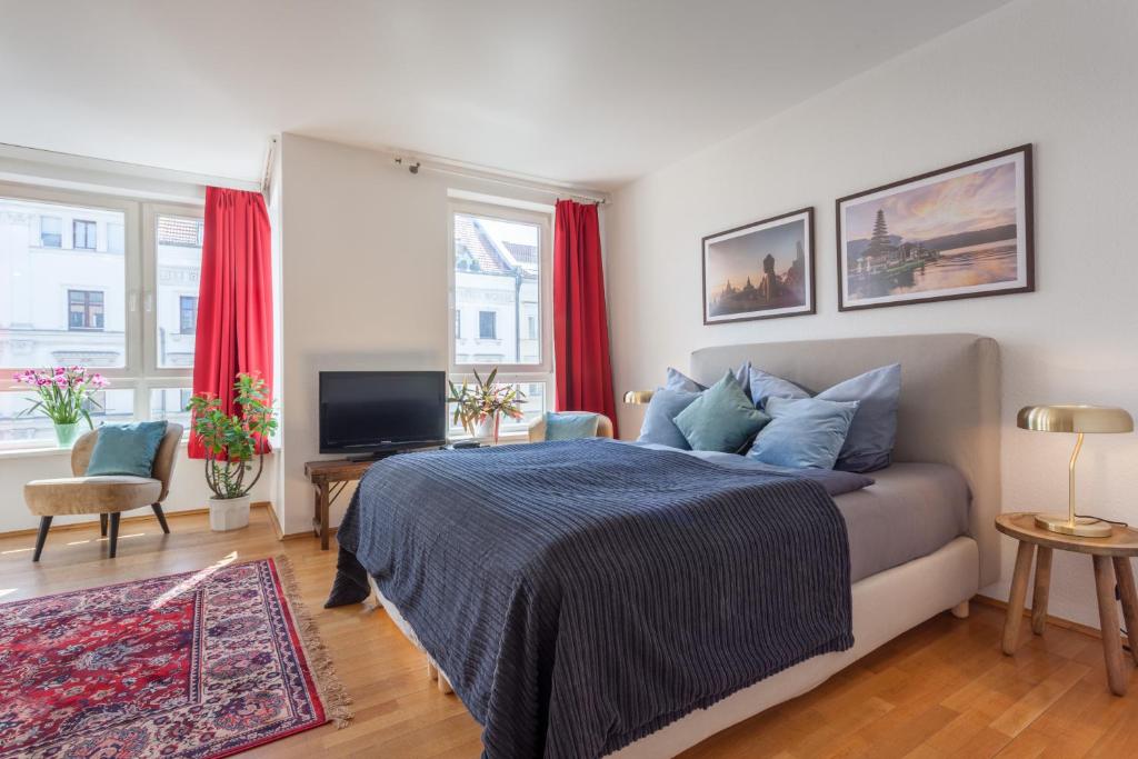 a bedroom with a bed and a television and red curtains at Stilvolles Studio in downtown Mitte, Boxspringbett, Balkon, Blick über Berlin auf den Himmel, zentrale Lage, Kiez vor der Haustür in Berlin