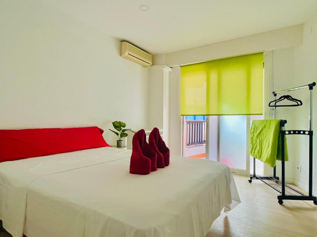 ein Schlafzimmer mit einem weißen Bett mit roten Kissen darauf in der Unterkunft Guest House Leo in Alicante