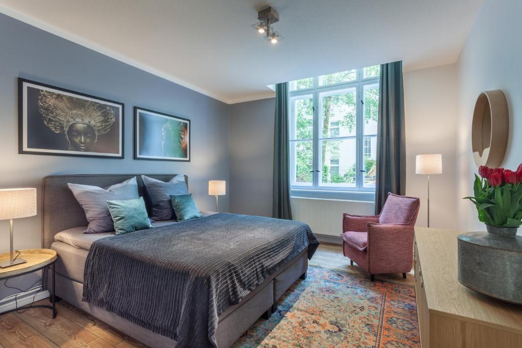 a bedroom with a bed and a chair and a window at The Paul II - stylish & central 3 BR apartment, group & family friendly, 4- 6 Guests in Berlin