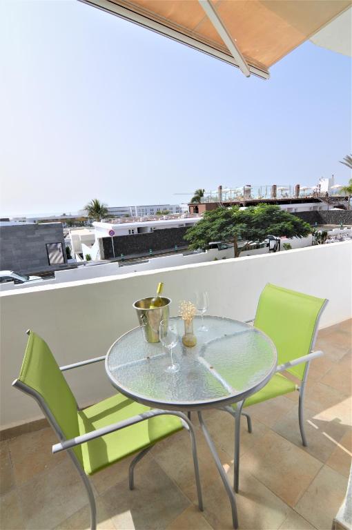 a glass table and two green chairs on a balcony at Apartamento Martina in Puerto del Carmen