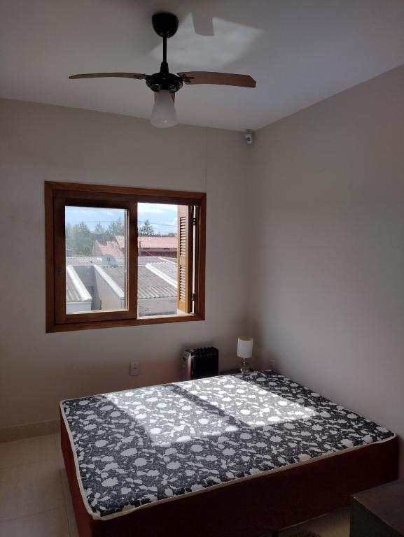 um quarto com uma cama e uma janela em Sobrado Praia Nova Tramandaí em Tramandaí