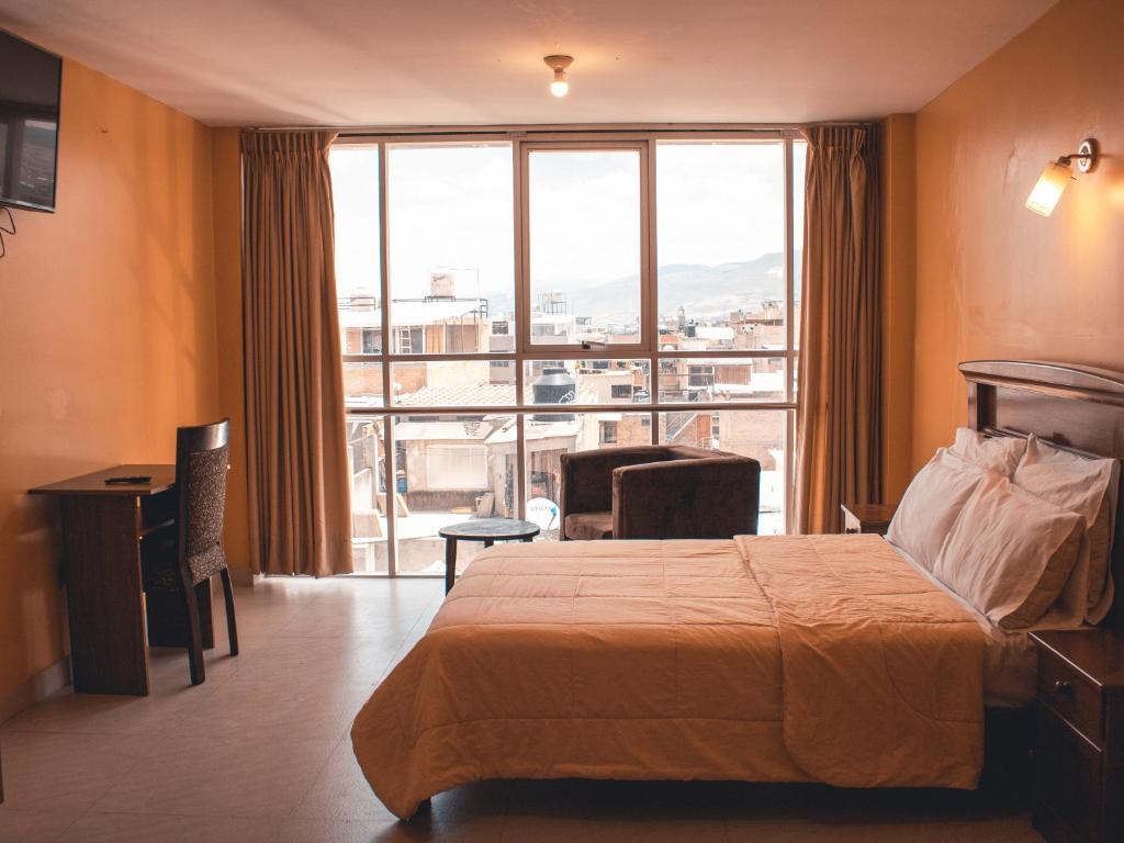 um quarto de hotel com uma cama e uma grande janela em Marzano em Cajamarca
