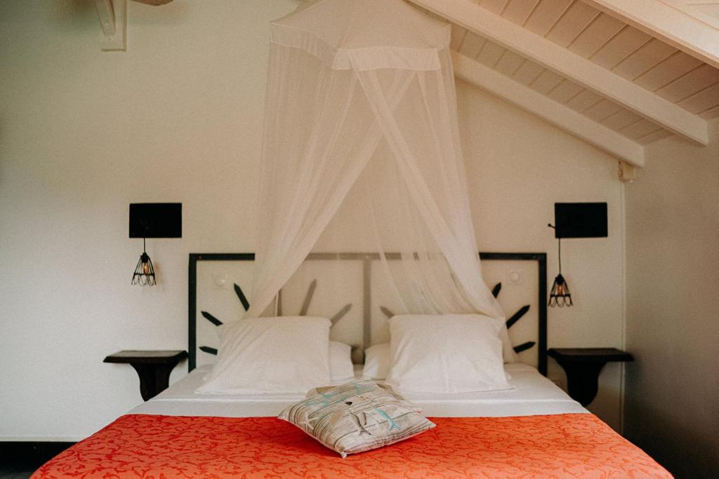 a bedroom with a bed with a red comforter at Caraib'Bay Hotel in Deshaies