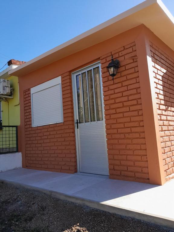 ein rotes Backsteinhaus mit einer weißen Tür in der Unterkunft Apartamento en Colonia in Colonia del Sacramento