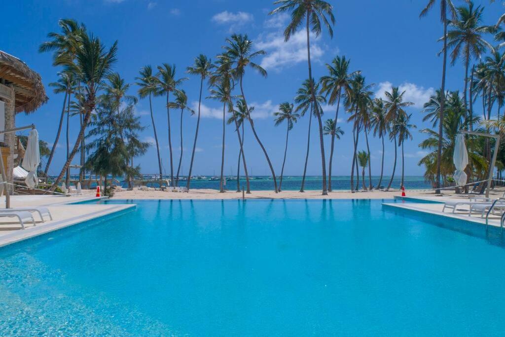 einen Pool mit Palmen und Strand in der Unterkunft Playa Coral Condo in Paradise F22 in Punta Cana