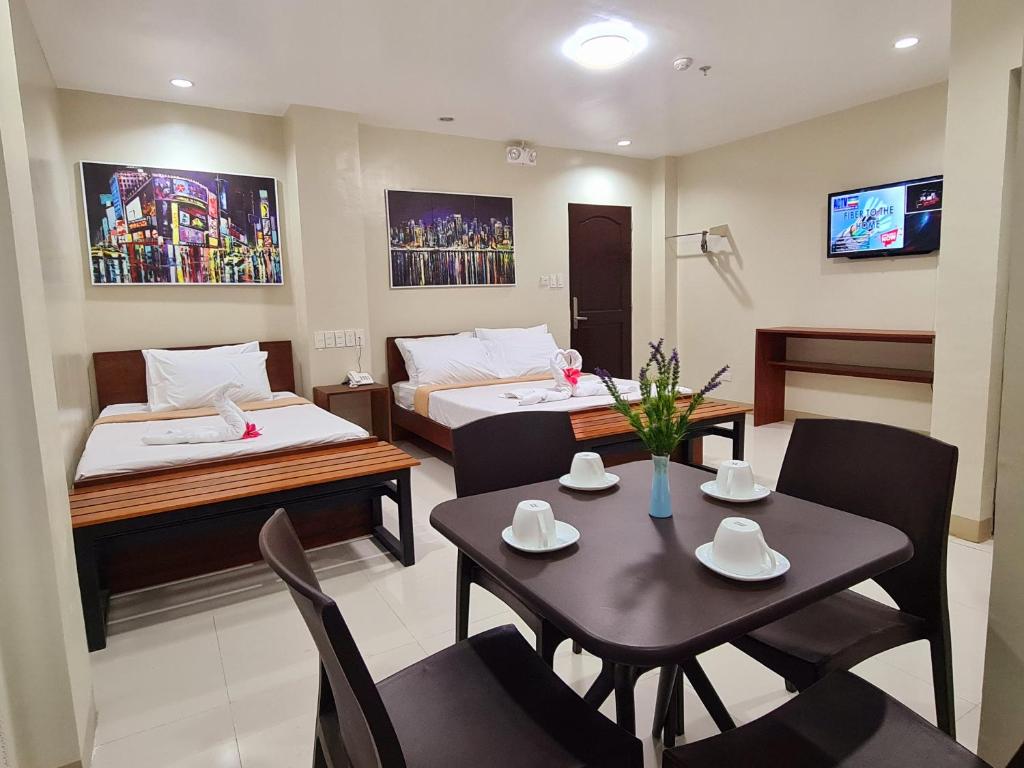 a room with two beds and a table and chairs at Grace & RB Hotel in Kalibo