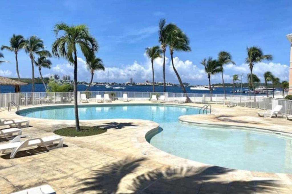 a swimming pool with palm trees in a resort at Appartement spacieux au village du flamboyant in Baie Nettle