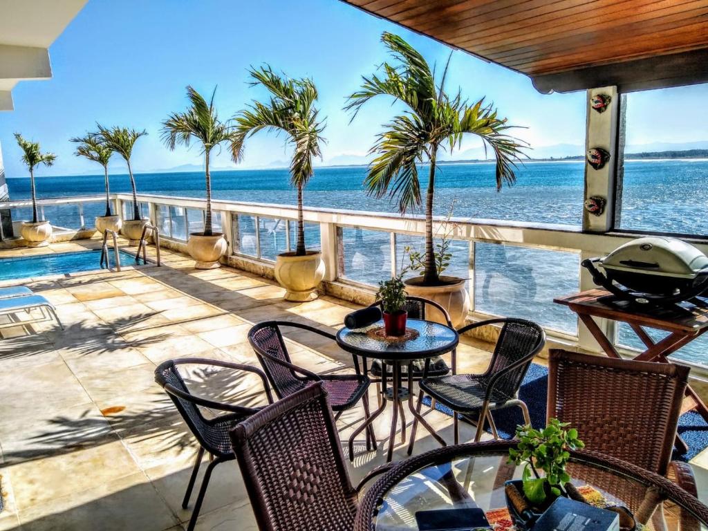 a patio with a table and chairs and the ocean at Marambaia Mar in Rio de Janeiro