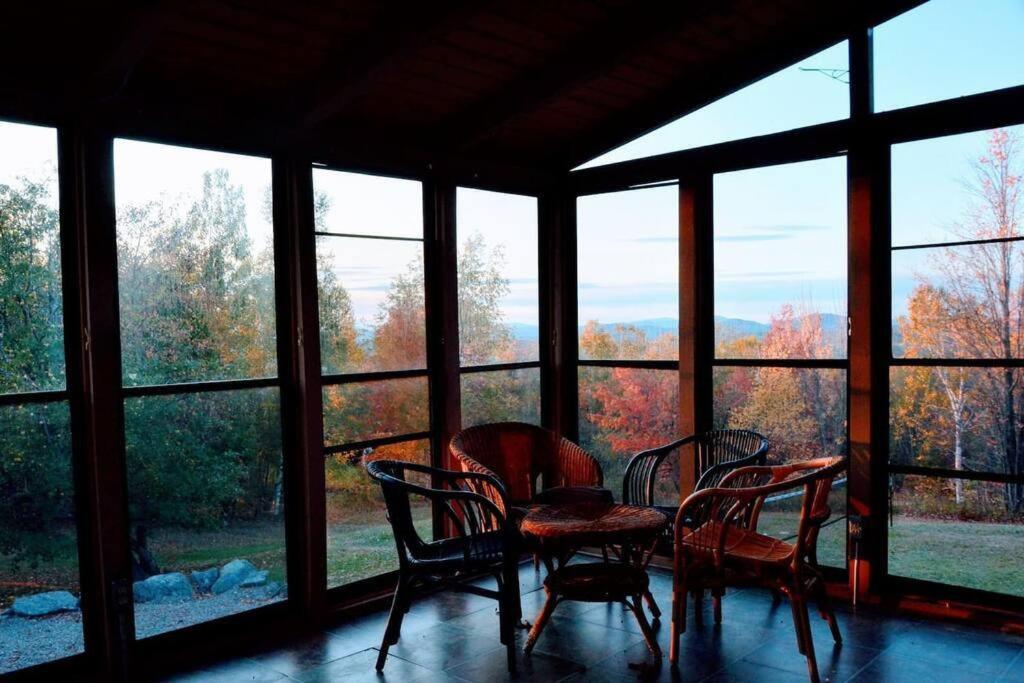 um quarto com uma mesa e cadeiras em frente às janelas em Beautiful White Mountain Cottage with Hot Tub em Jefferson