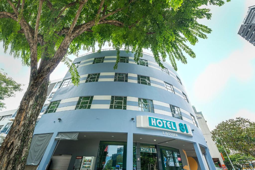 a building with a hotel sign in front of a tree at Hotel 81 Lavender in Singapore