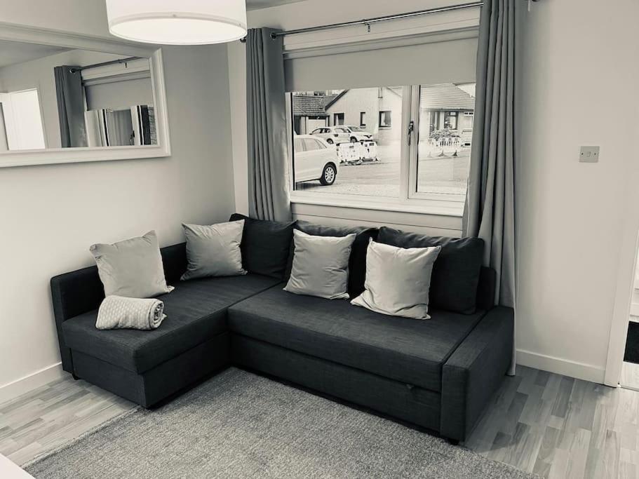 a black couch in a living room with a window at Beautiful refurbished, self-contained apartment in Fife