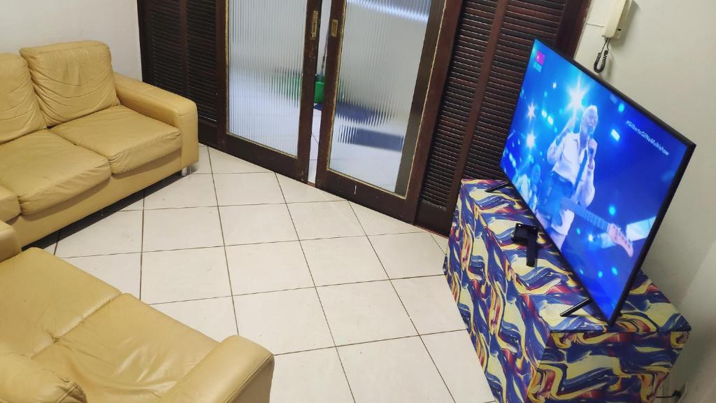 een woonkamer met een bank en een flatscreen-tv bij Hostel da Floresta in Vitória