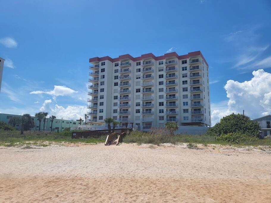 un gran edificio de apartamentos en la playa con un banco en Updated Oceanfront Condo! Come Relax by the Sea!, en Ormond Beach