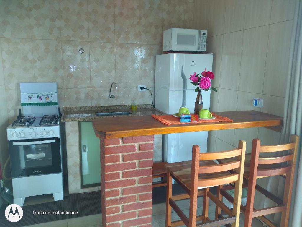 a kitchen with a counter with a stove and a refrigerator at Chalé Tarumã in Gonçalves