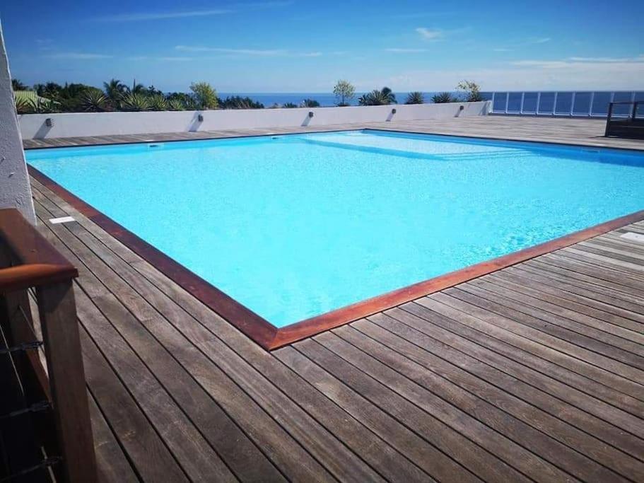 une grande piscine bleue sur une terrasse en bois dans l'établissement Farerei Appartement spacieux, équipé et confortable, à Fa'a'ā