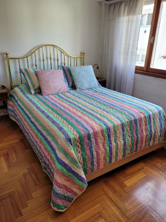 Una cama con una manta colorida y almohadas. en Dpto. amplio y luminoso en Mar del Plata