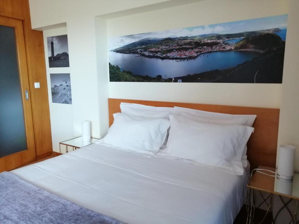 a bedroom with a white bed with a picture on the wall at Apartamento Avenida - AL 1798 in Horta
