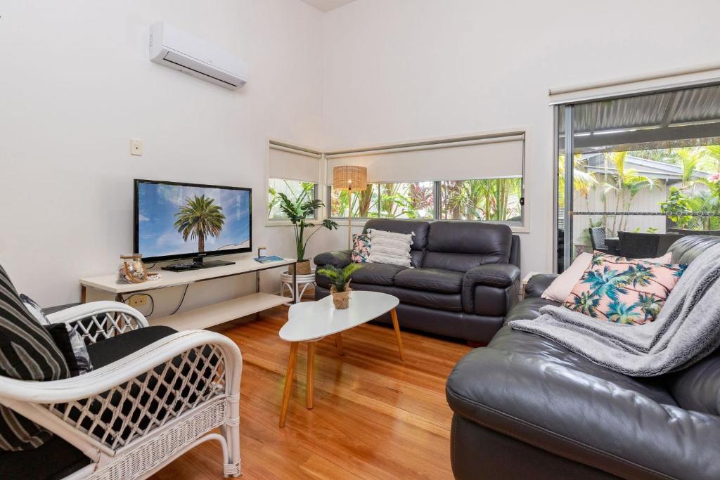 a living room with a leather couch and a tv at Mobys Resort 35 in Boomerang Beach