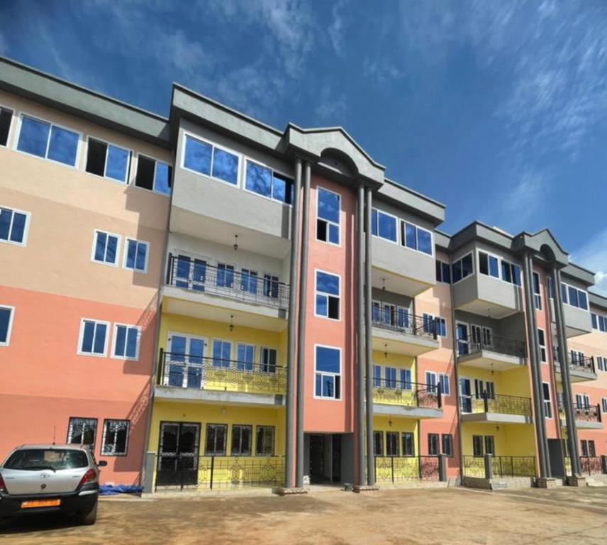 an apartment building with a car parked in front of it at Primeshare Luxury Apartments Ebang - Swimming Pool, Snack, Sports, & Tech Center in Yaoundé