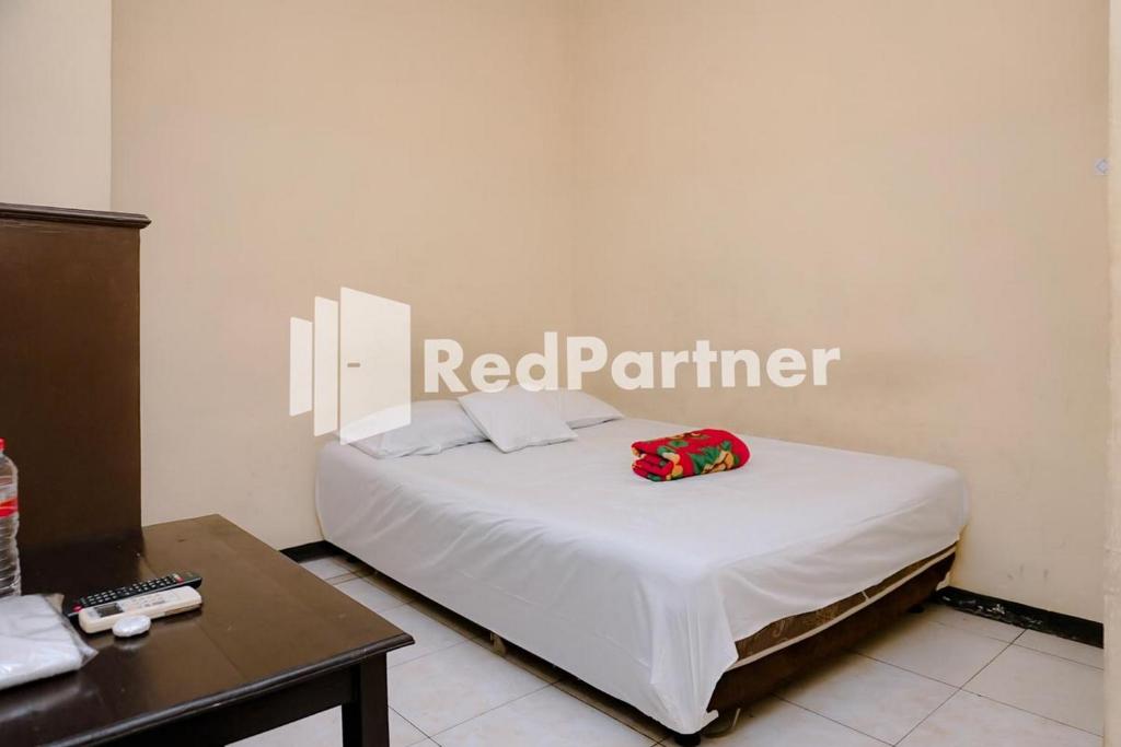Bett in einem Zimmer mit einem roten Partnerschild an der Wand in der Unterkunft Sawojajar Inn Mitra RedDoorz in Malang