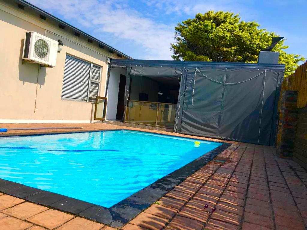 a swimming pool in front of a house at Cozy Corner Guesthouse in Richards Bay