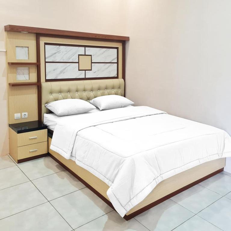 Un dormitorio con una gran cama blanca y una ventana en RedDoorz @ Jalan Nyai Enat Sampit en Sampit