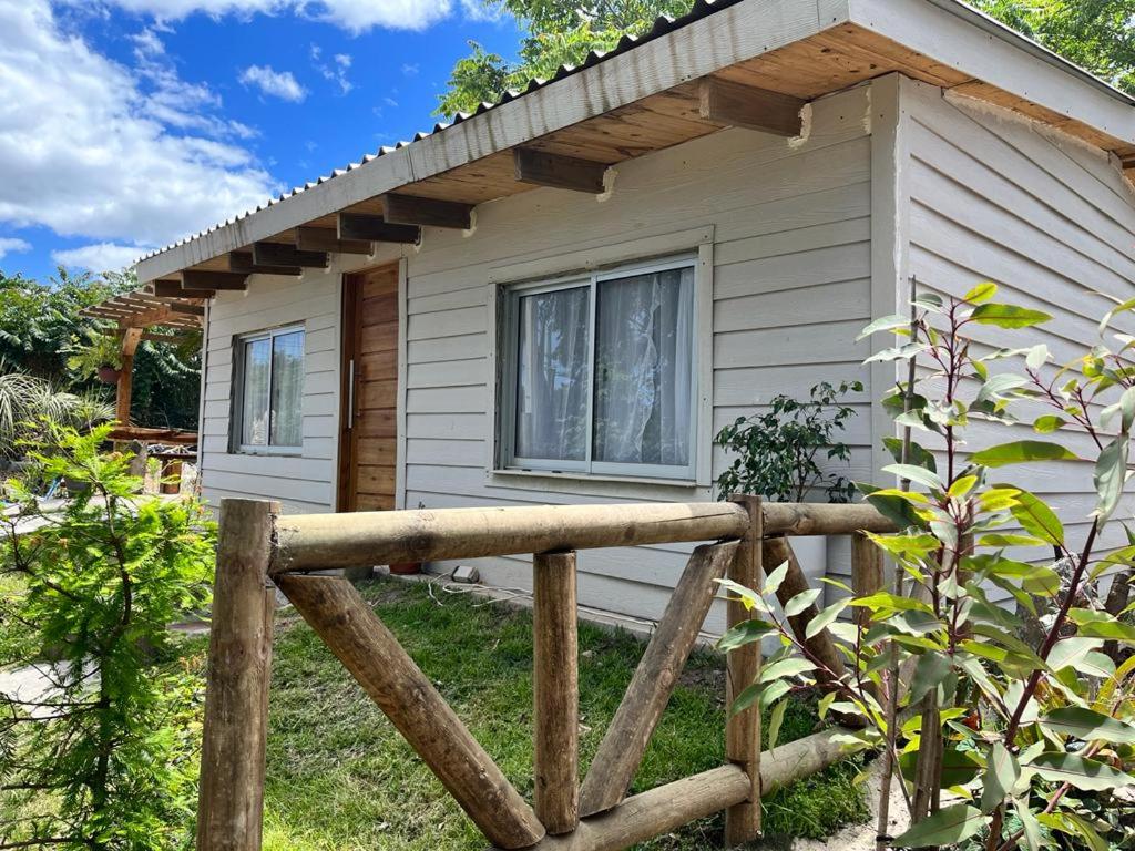 una pequeña casa con una valla de madera delante de ella en Complejo El Refugio - Las Toscas en Las Toscas