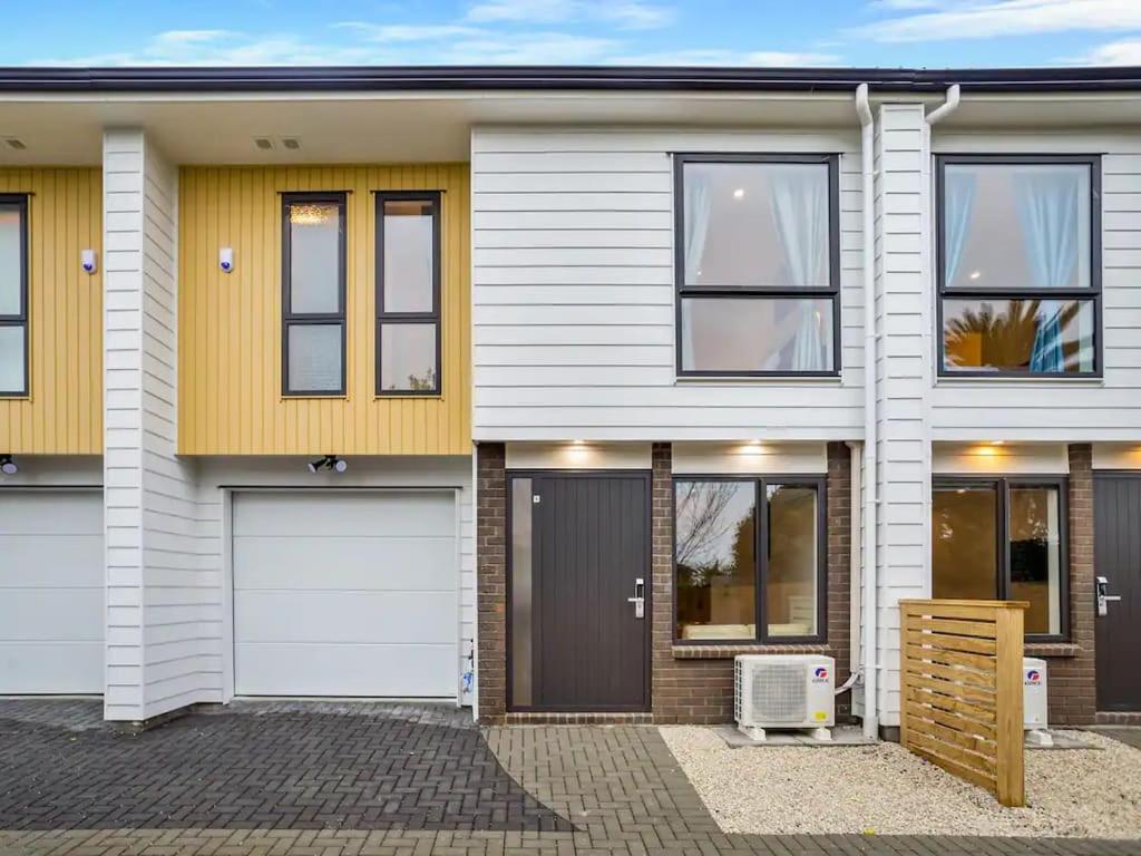 a house with a white and yellow facade at Wonderful Three Bedroom with Garage in Auckland