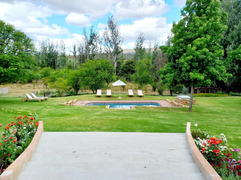 a walkway leading to a garden with a swimming pool at Aloe Valley Retreat in Oudtshoorn