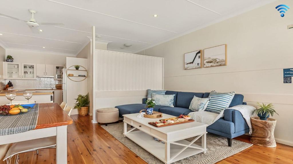 ein Wohnzimmer mit einem blauen Sofa und einem Tisch in der Unterkunft Ocean Blue Apartment Two in Currarong