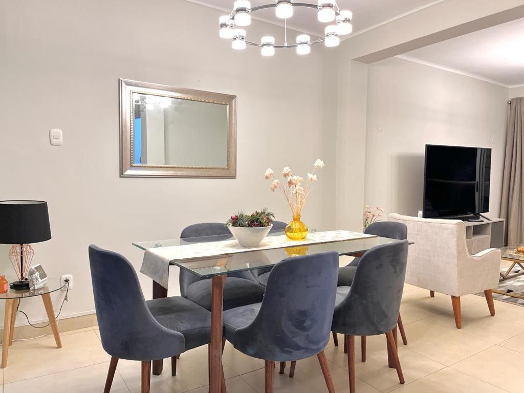 a dining room with a table and chairs and a television at Apartamento en el Corazon de Miraflores in Lima