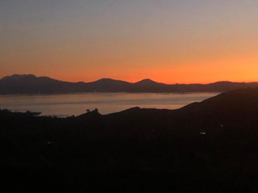 una puesta de sol sobre un cuerpo de agua con montañas en Whakaipo Bay Cabin Retreat Taupo, en Taupo