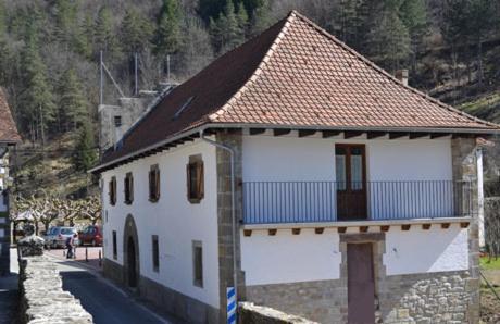 a white building with a brown roof on a street at Alojamientos Rurales Apezarena in Izalzu