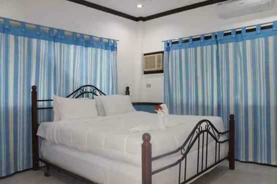 a bedroom with a large white bed with blue curtains at Arapal Nature Retreat in Bogo