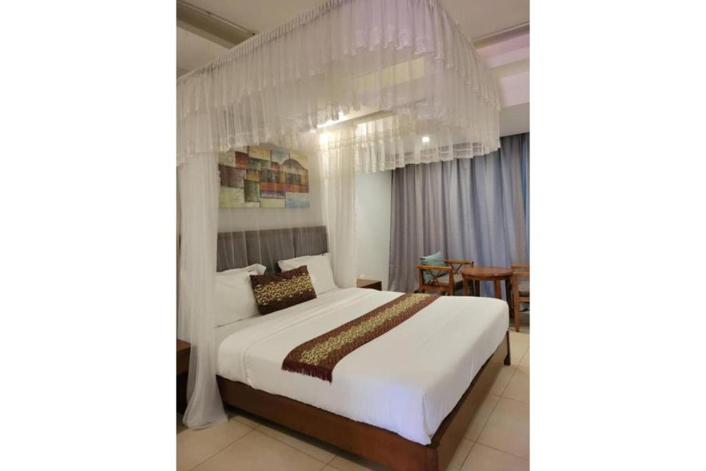 - une chambre avec un grand lit blanc et un lustre dans l'établissement Acholi Inn, à Gulu