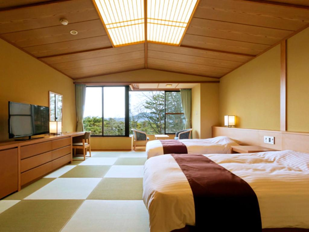 a hotel room with two beds and a flat screen tv at Jodogahama Park Hotel in Miyako