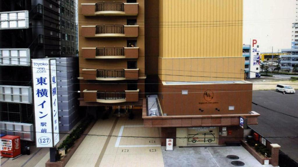 un edificio alto con un banco delante de él en Toyoko Inn Mikawa anjo eki Shinkansen Minami guchi No 1, en Anjomachi