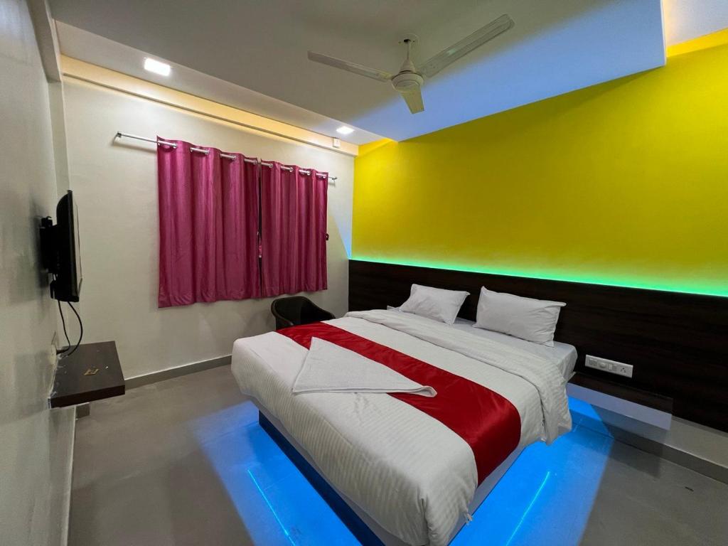 a bedroom with a bed with a red and yellow wall at Sayba Inn Lodging in Pune