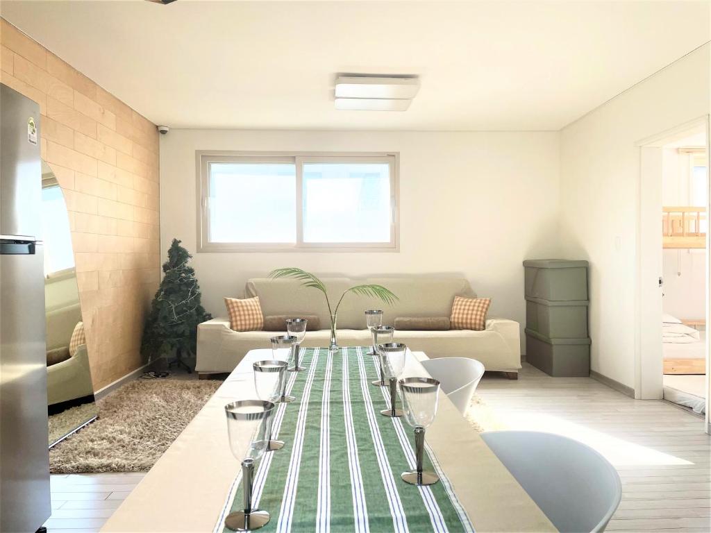 ein Wohnzimmer mit einem Tisch und Weingläsern darauf in der Unterkunft Koin Guesthouse Incheon airport in Incheon