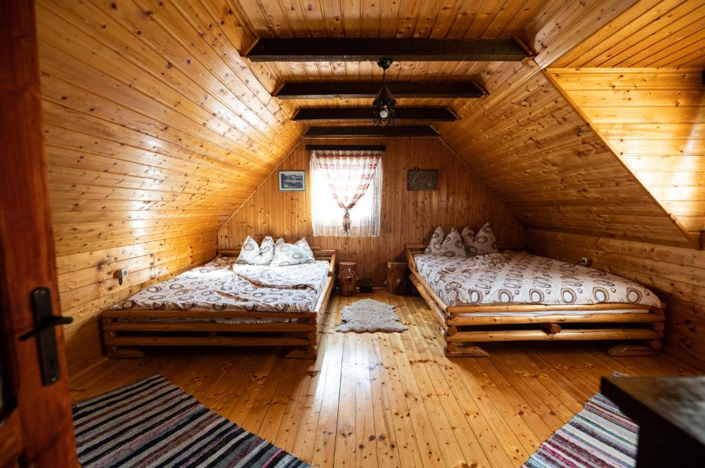 una camera con due letti in una cabina di legno di Casa de vacanta Vidrighin a Rau Sadului