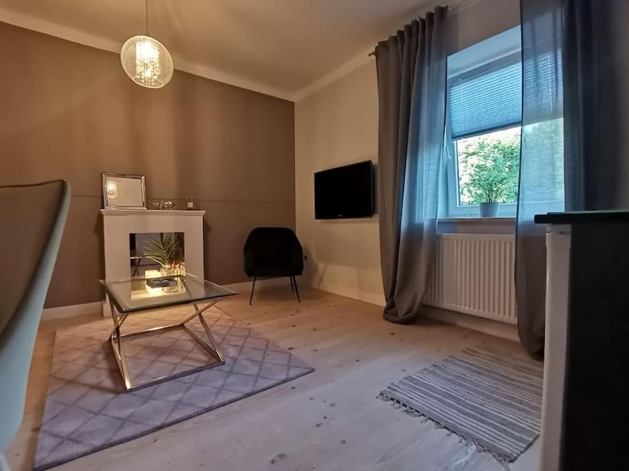 a living room with a glass table and a window at Apartamenty Motyl - pokój studio in Bytom