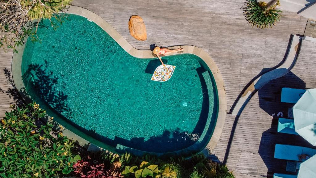 una vista aérea de una piscina con una persona en el agua en Ecozy Dijiwa Canggu en Canggu