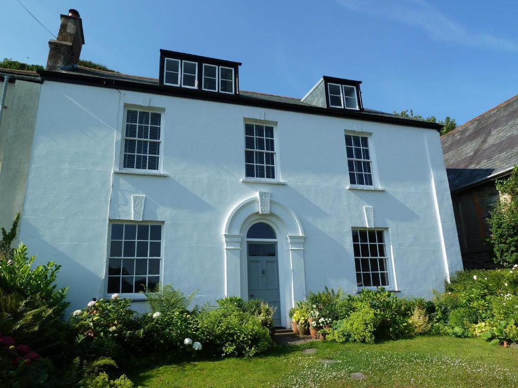 林頓的住宿－Beautiful 6-Bed House in Lynton North Devon，白色的房子,有门和院子